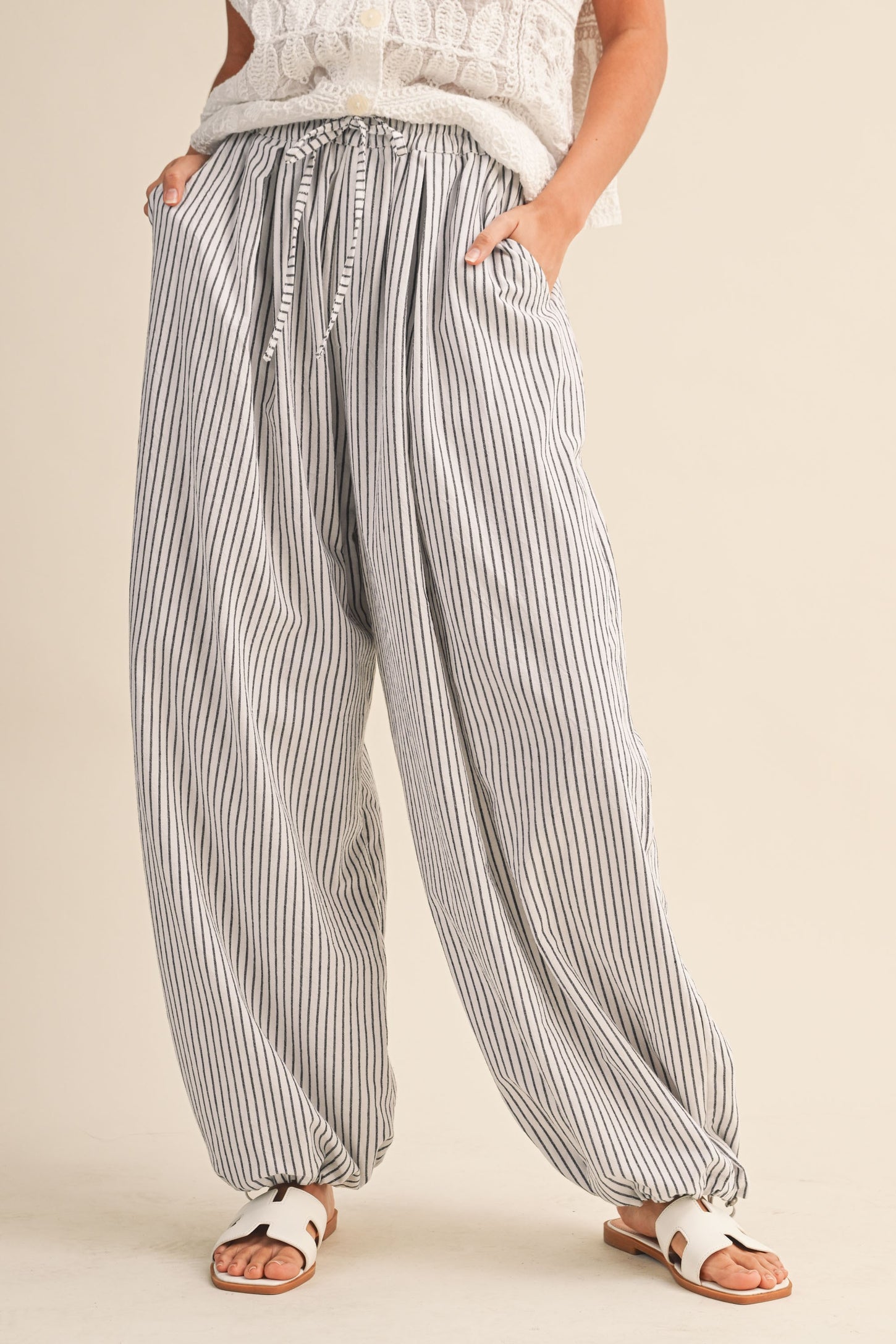 woman wearing high-waisted striped wide-leg pants with side pockets and a relaxed fit, styled with a loose top and sandals