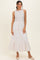 woman wearing a light beige sleeveless top and a long floral print skirt with a tiered hem and drawstring waist