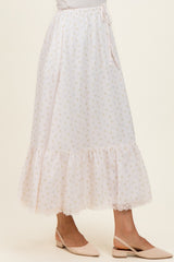 woman wearing a pastel pink floral print maxi skirt with a ruffled hem and a drawstring waist