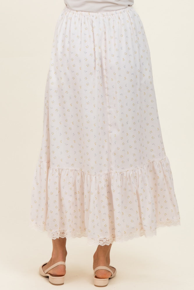 woman wearing a white floral print maxi skirt with a ruffled hem and lace details, viewed from the back
