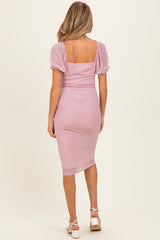 woman wearing a pink polka dot maternity dress with short puff sleeves and a fitted midi length