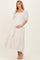 woman wearing a pink and white patterned maternity dress with puff sleeves and tiered skirt, holding her baby bump