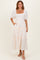 woman wearing a beige tiered maxi dress with puff sleeves and a square neckline, standing in front of a neutral background