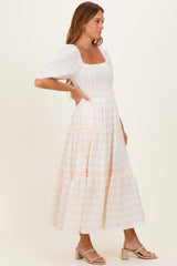woman wearing a white floral puff sleeve maxi dress with a square neckline and tiered skirt, side profile view