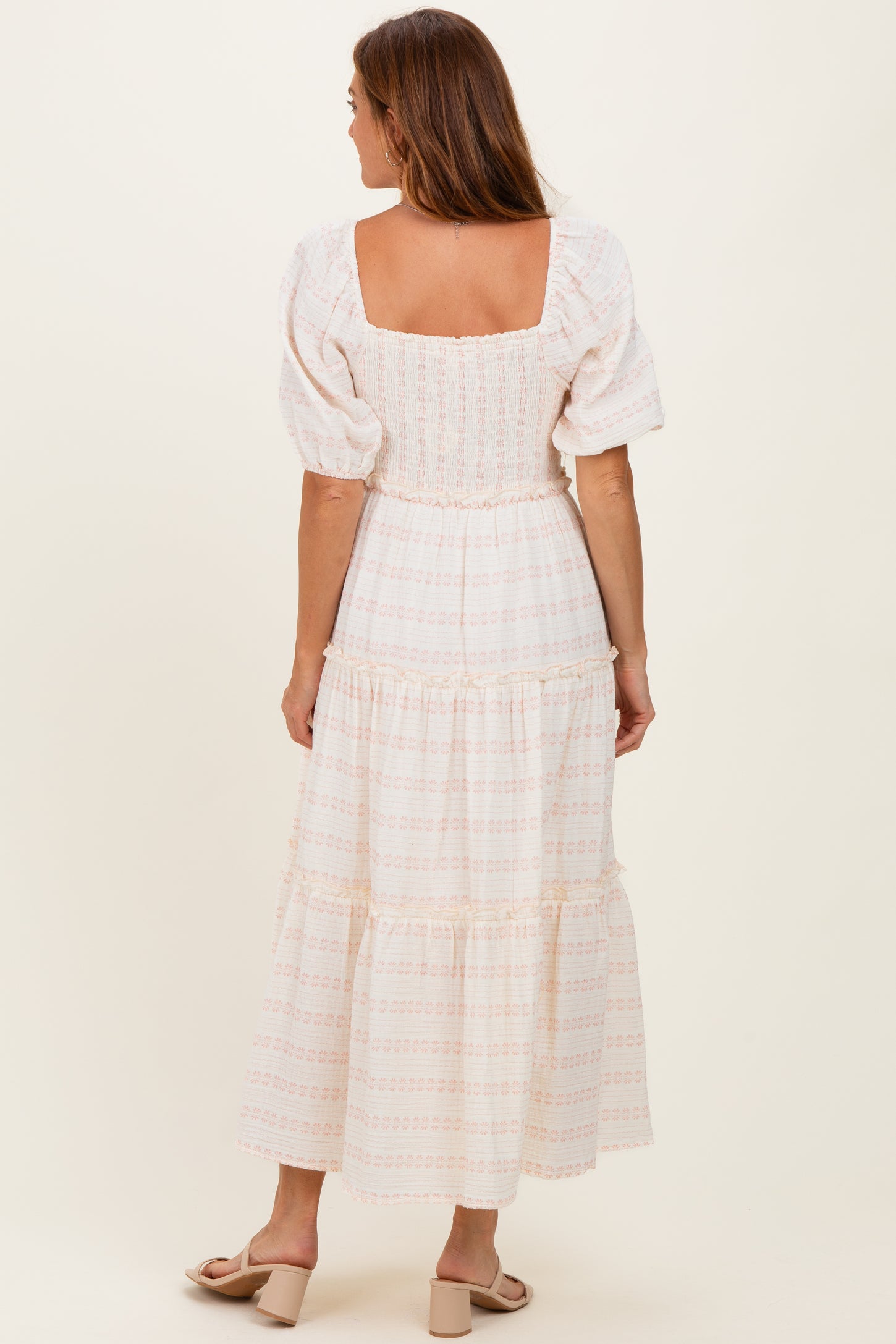 woman wearing a cream puff sleeve maxi dress with a smocked bodice and tiered skirt, shown from the back