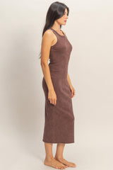 woman wearing a ribbed brown sleeveless midi dress standing sideways on a plain background