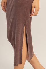 close-up of a woman wearing a mauve ribbed midi dress with a side slit detail