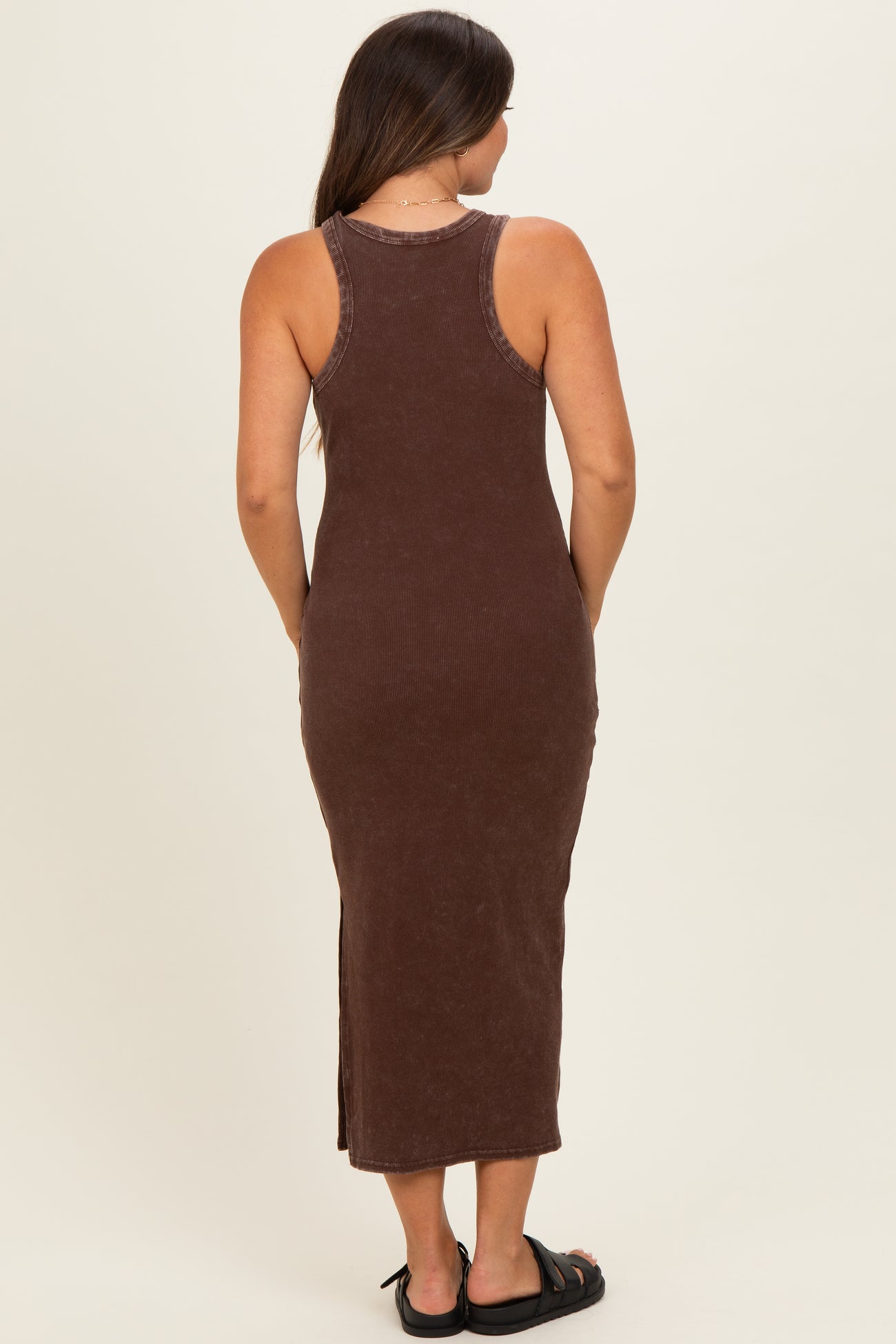 woman wearing a brown ribbed maternity maxi dress with side slit, showing the back view and a baby bump