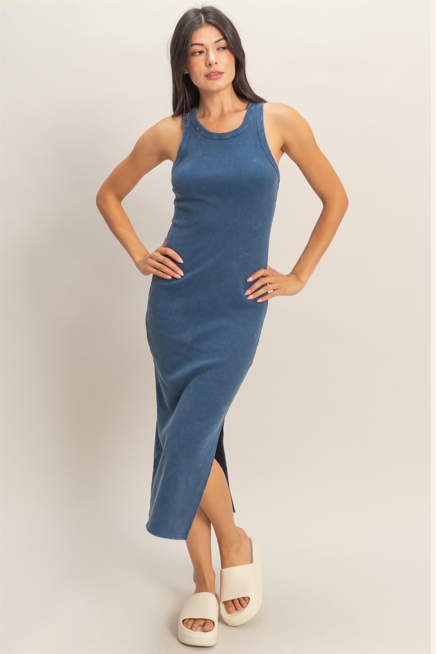 woman wearing a blue sleeveless midi dress with a side slit and a fitted silhouette