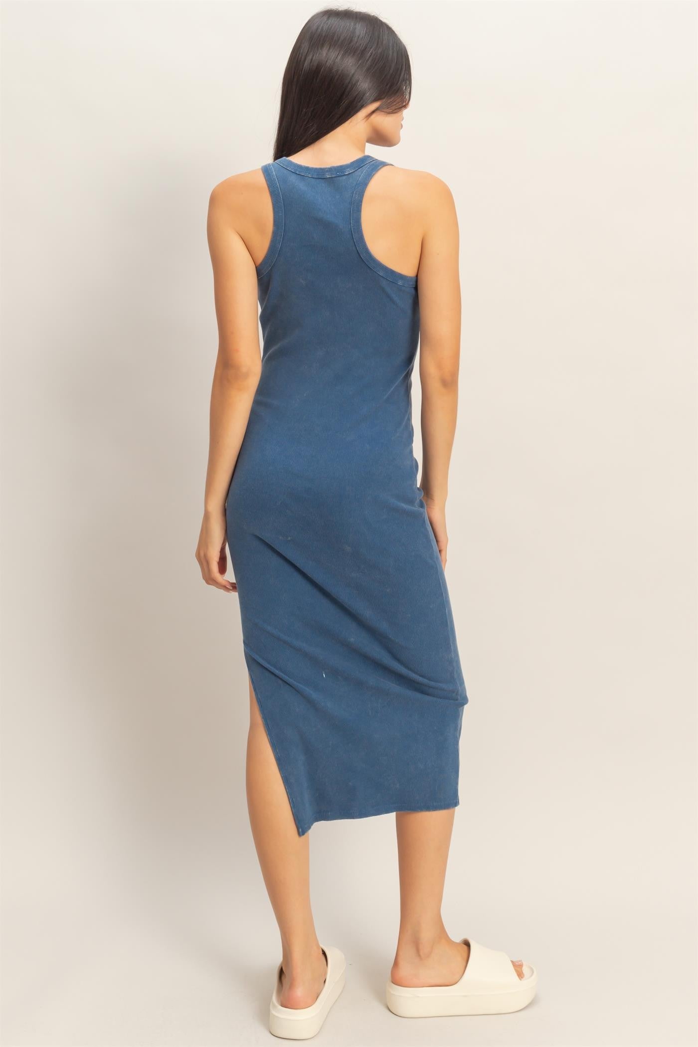 woman wearing a blue sleeveless maxi dress with a side slit and a fitted silhouette