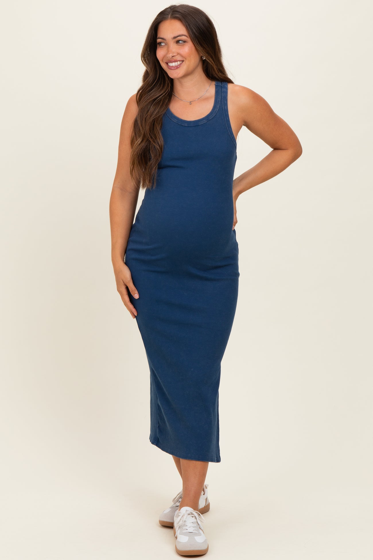 woman wearing a navy blue ribbed maternity maxi dress with a fitted silhouette and visible baby bump
