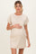 woman wearing a beige and cream striped maternity dress and holding her baby bump
