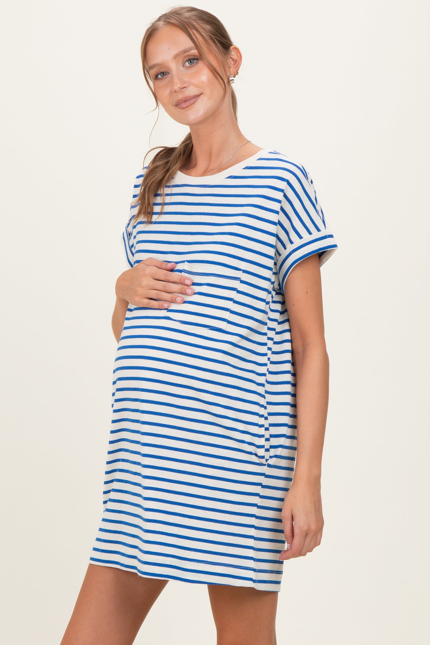 woman wearing a striped maternity dress with blue and white horizontal stripes and holding her baby bump