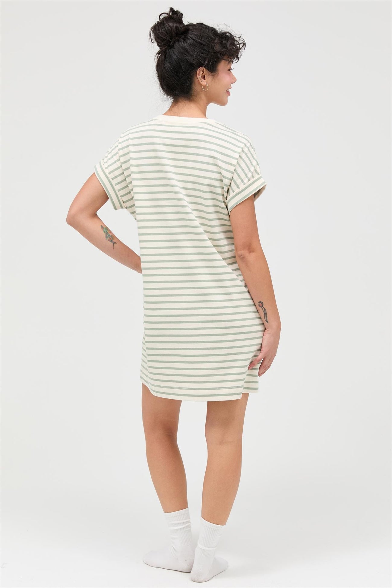 woman wearing a striped oversized t-shirt dress with rolled sleeves, facing away from the camera
