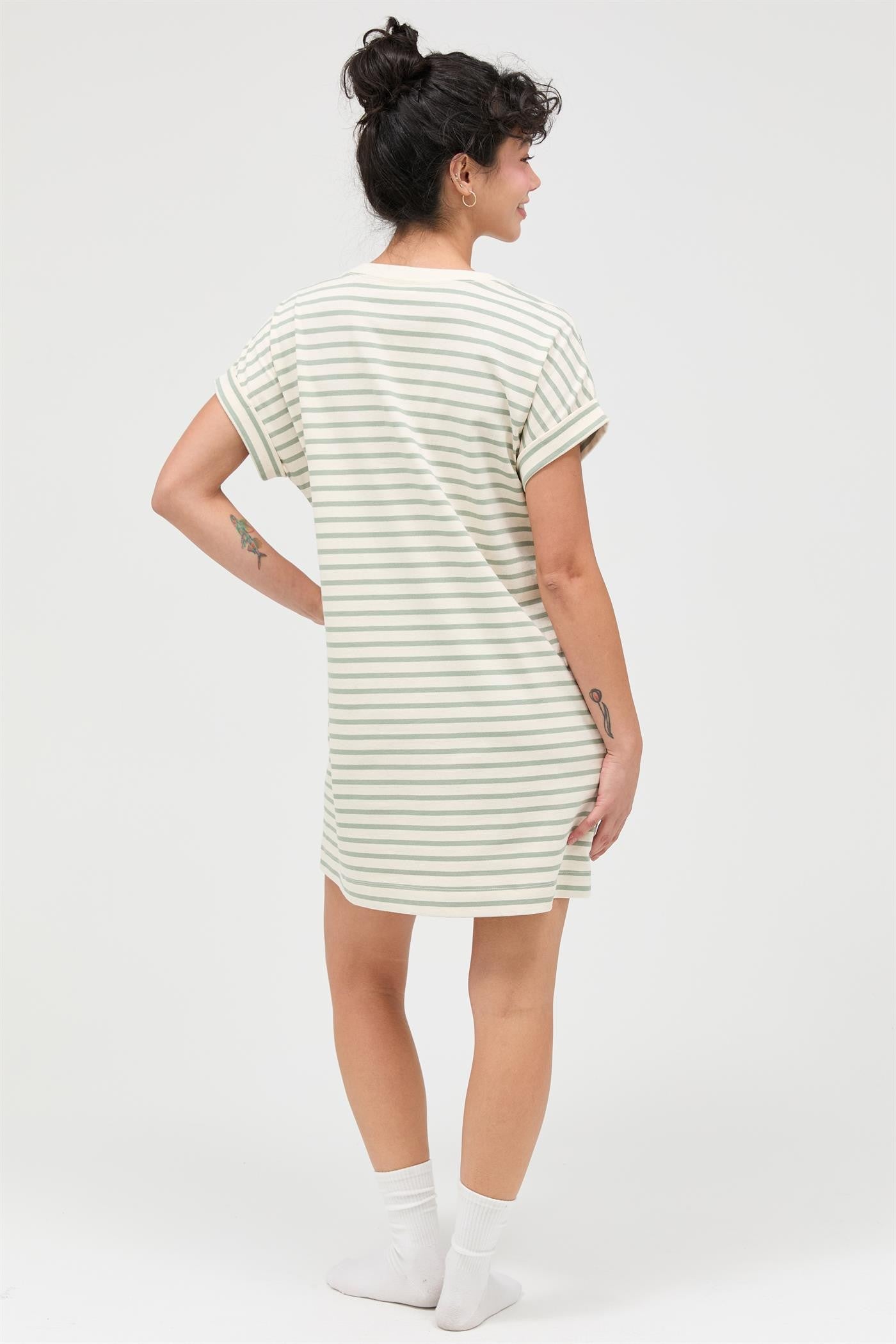 woman wearing a striped oversized t-shirt dress with rolled sleeves, facing away from the camera