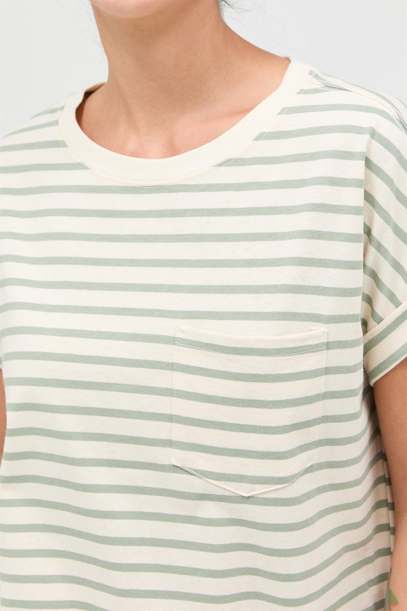 woman wearing a cream and green striped short sleeve top with a chest pocket