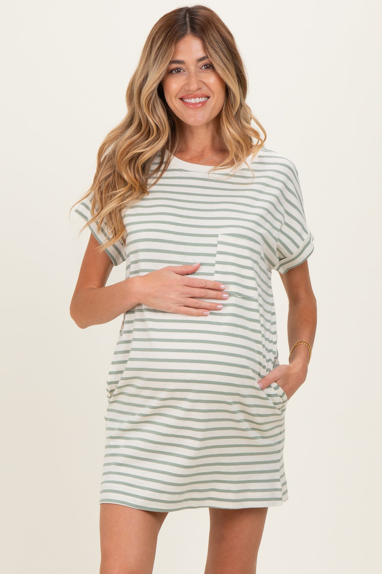 woman wearing a striped maternity t-shirt dress with pockets and holding her baby bump