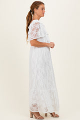 woman wearing a white lace maxi dress with ruffled sleeves and a tiered design