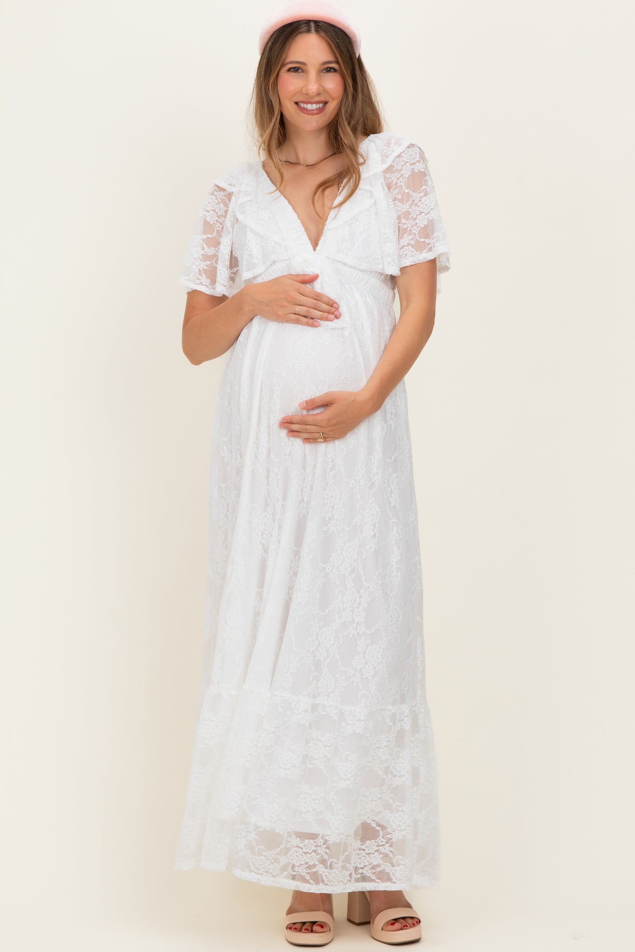 woman wearing a white lace maternity maxi dress and holding her baby bump