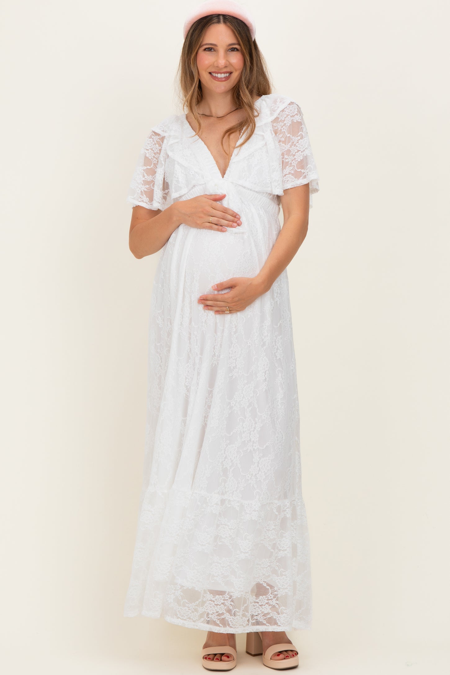 woman wearing a white lace maternity maxi dress and holding her baby bump