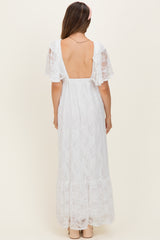 woman wearing a white lace maternity maxi dress with flutter sleeves and an open back