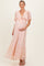 woman wearing a light peach lace maternity maxi dress with a bow detail and holding her baby bump