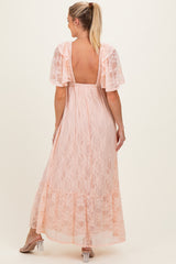 woman wearing a light pink lace maternity maxi dress with short sleeves and a backless design