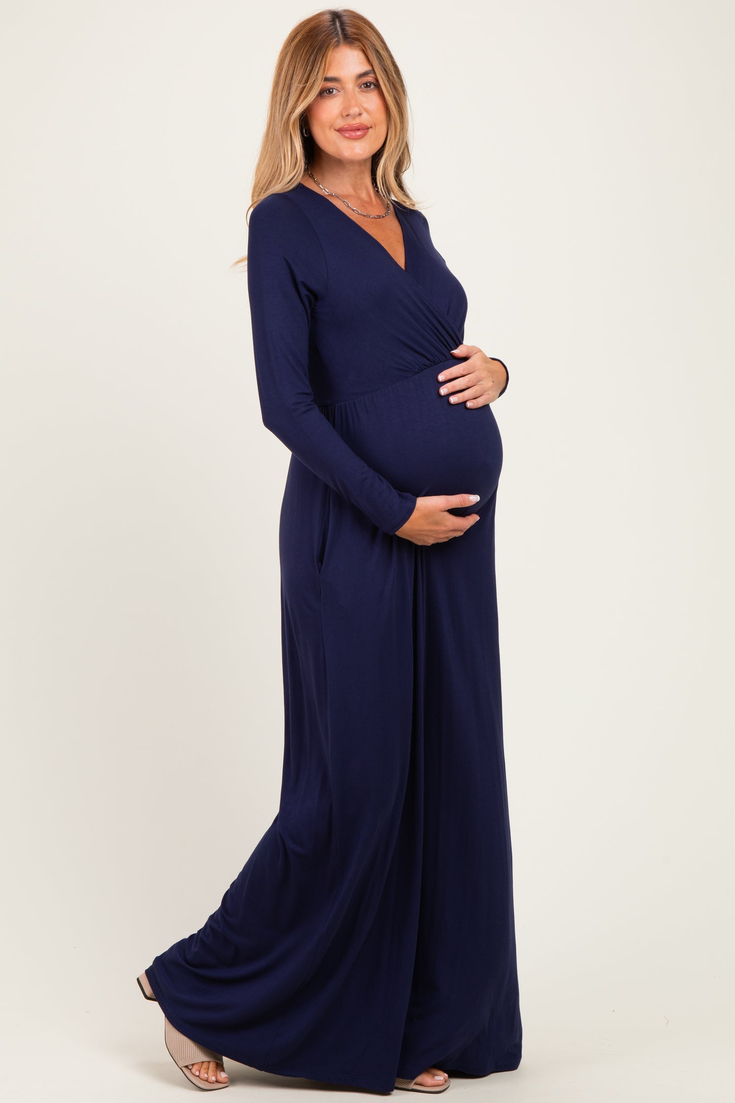 woman wearing a navy blue long sleeve maternity dress and holding her baby bump