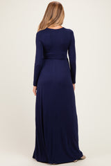 woman wearing a navy blue long sleeve maternity maxi dress, view from the back showing the flowing fabric and fitted waist