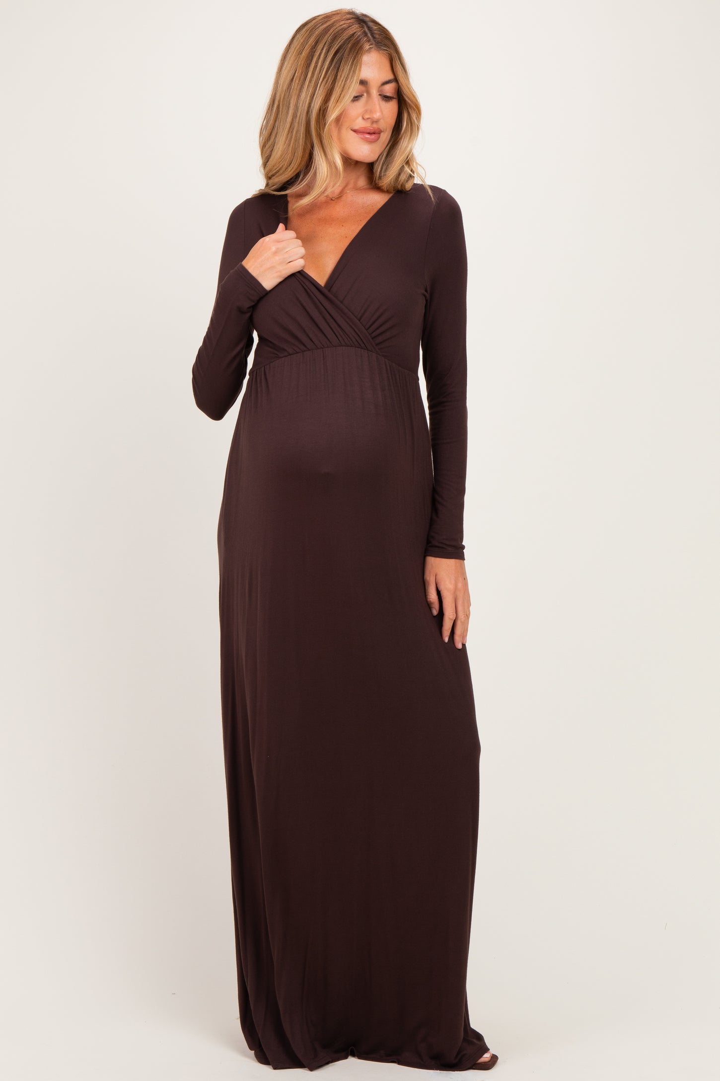 woman wearing a brown long sleeve maternity dress with a wrap style and a visible baby bump