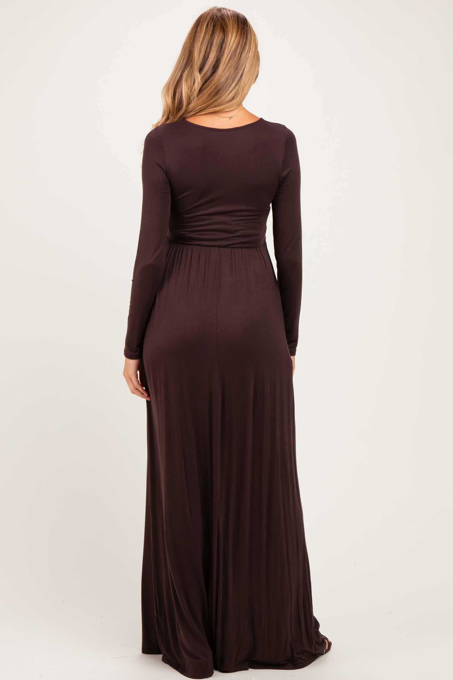 woman wearing a chocolate brown long sleeve maternity maxi dress seen from the back