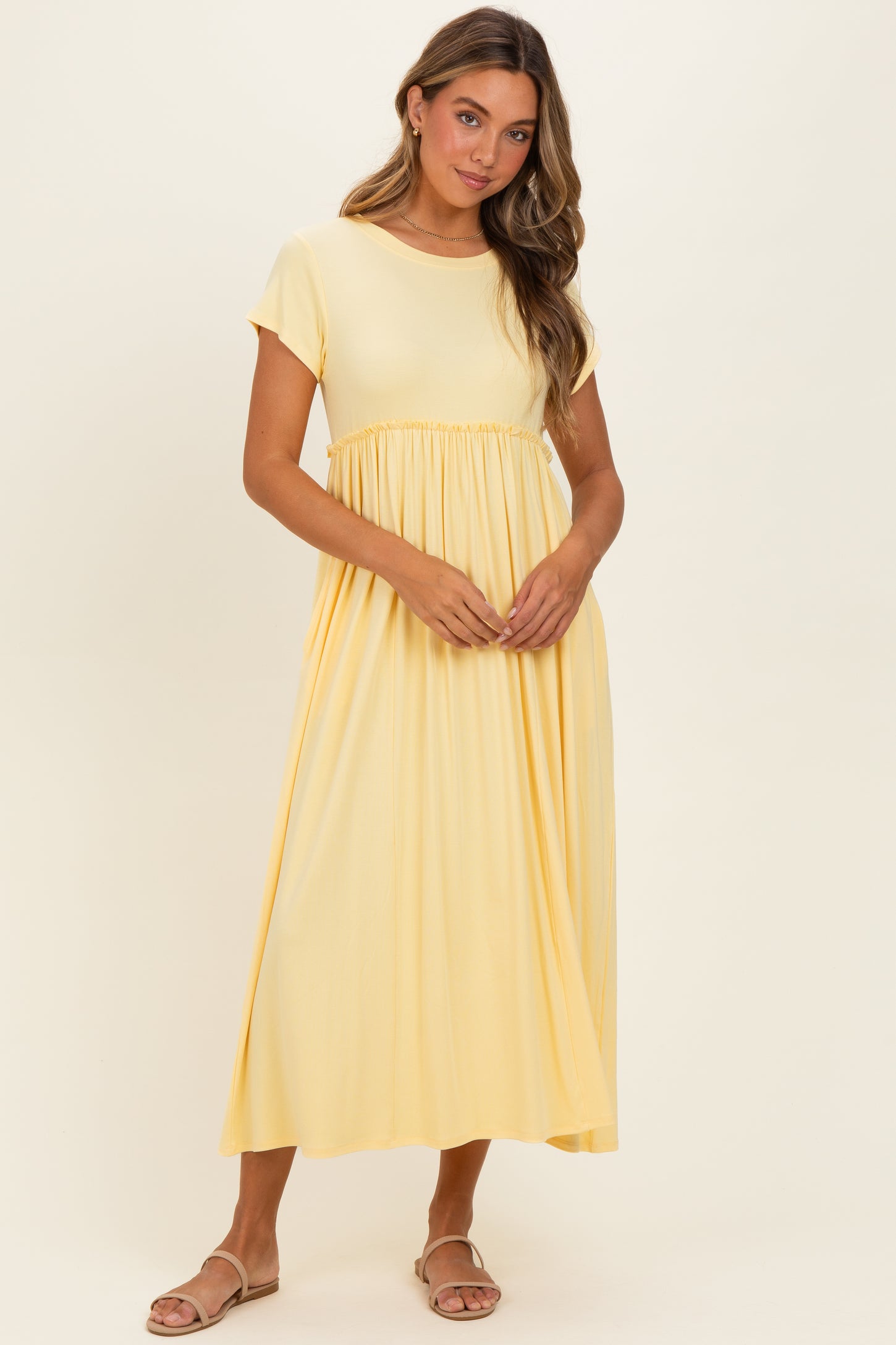 woman wearing a yellow short sleeve maxi dress with a gathered waist and flowy skirt