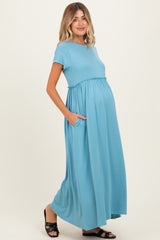woman wearing a blue short sleeve maternity maxi dress with pockets and a visible baby bump