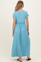woman wearing a light blue maternity maxi dress with a cinched waist and short sleeves, showing her baby bump