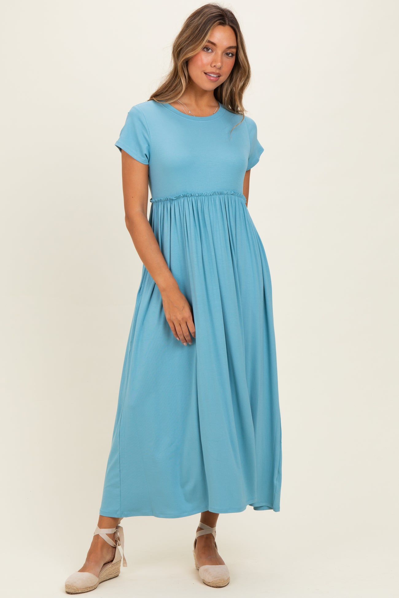 woman wearing a light blue short sleeve maxi dress with a gathered waist and flowy skirt