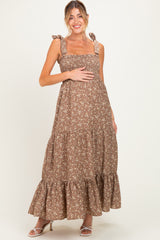 woman wearing a brown floral maternity maxi dress with tie straps and a visible baby bump