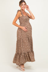 woman wearing a brown floral maternity maxi dress with tie straps and a visible baby bump