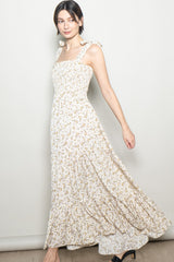 woman wearing a white floral maxi dress with tie straps and a smocked bodice, twirling to show the flowy skirt