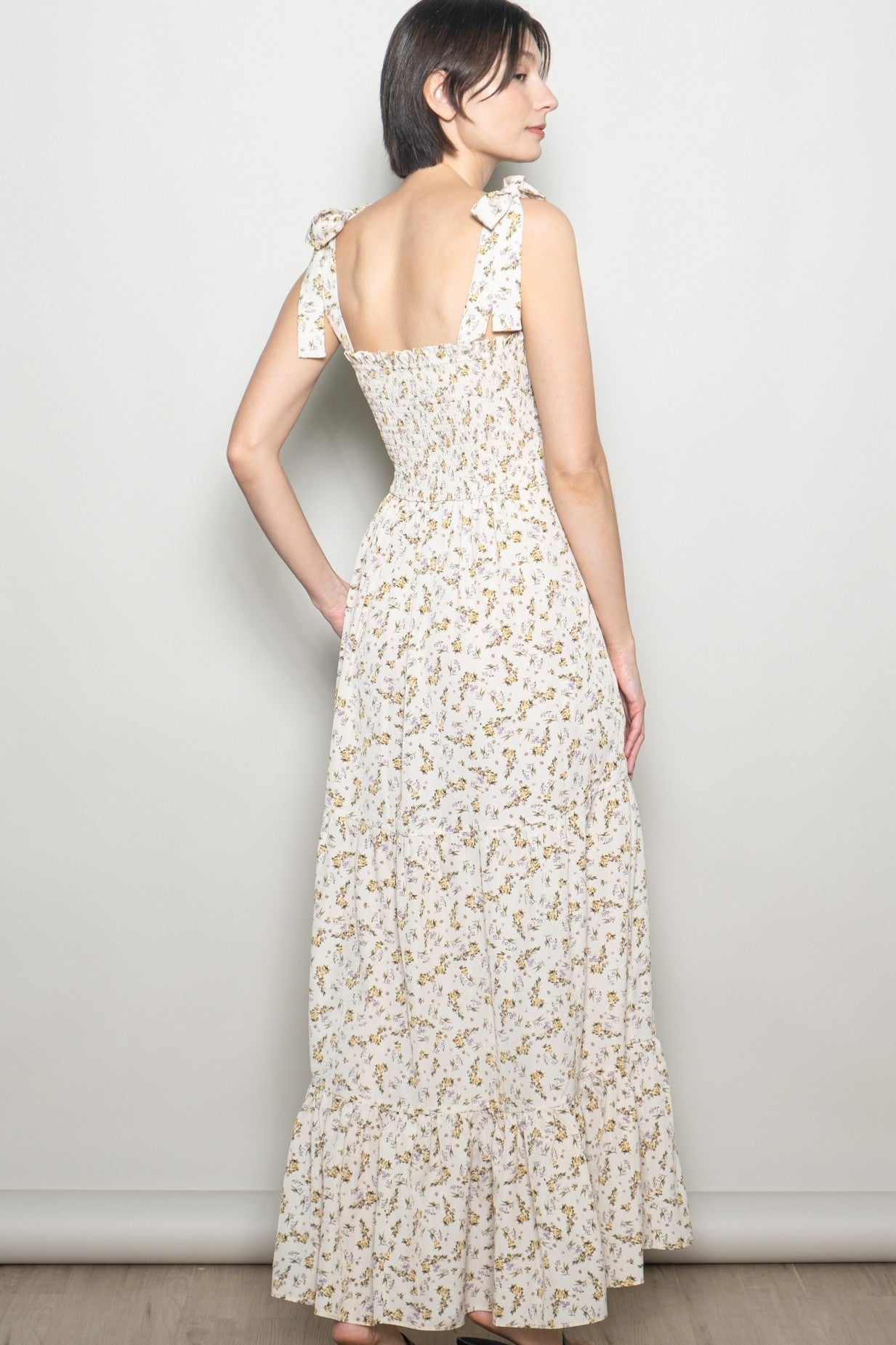 woman wearing a white floral maxi dress with ruffled straps and a smocked back