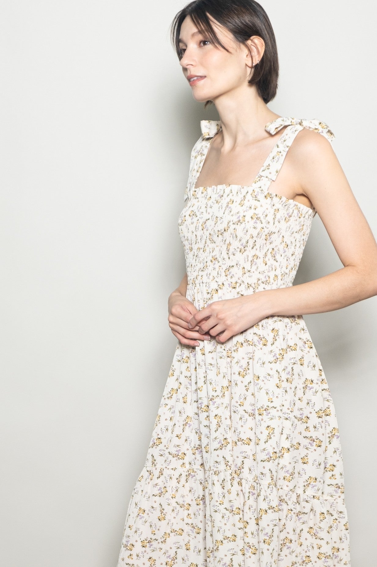 woman wearing a floral print square neck dress with tie straps and a flowy skirt