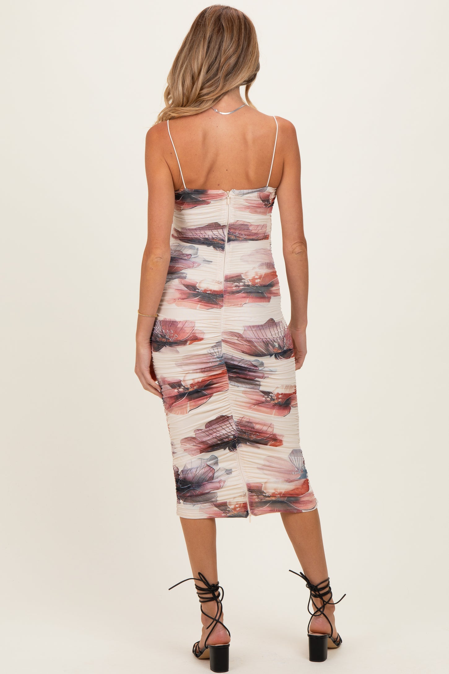 woman wearing a floral print maternity dress with a fitted silhouette and spaghetti straps, showing a smooth back view