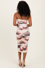 woman wearing a form-fitting midi dress with a floral print and spaghetti straps, showing the back design
