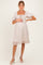 woman wearing a light pink maternity dress with puff sleeves and a square neckline, featuring a ruffled hem