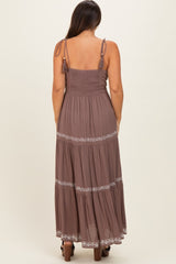 woman wearing a brown maternity maxi dress with adjustable straps and embroidered details on the tiers