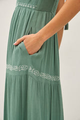 close-up of a woman’s green maxi dress with embroidered details and a side pocket