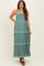 woman wearing a green maternity maxi dress with thin straps and embroidered details, holding her baby bump