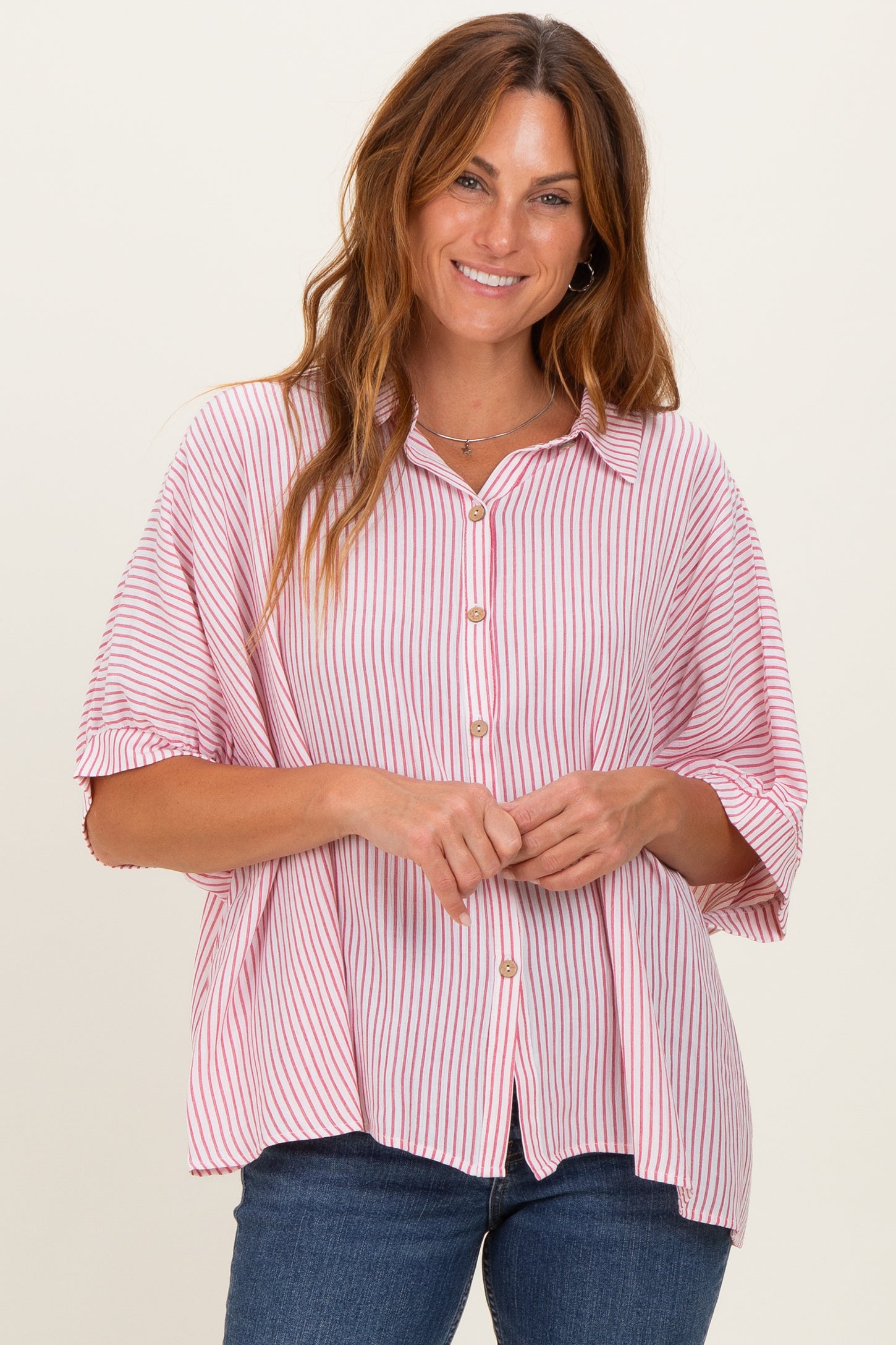 woman wearing a pink and white striped button-up shirt with a relaxed fit and short sleeves