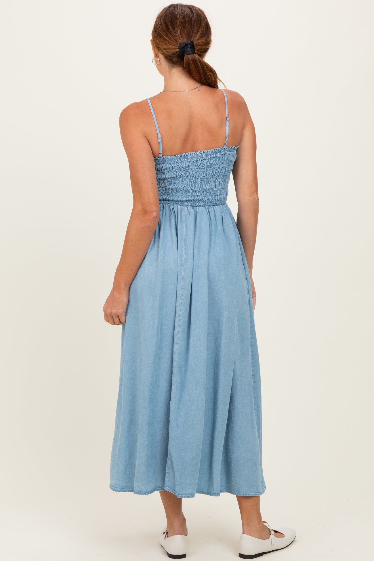 woman wearing a light blue maxi dress with smocked bodice and spaghetti straps, shown from the back