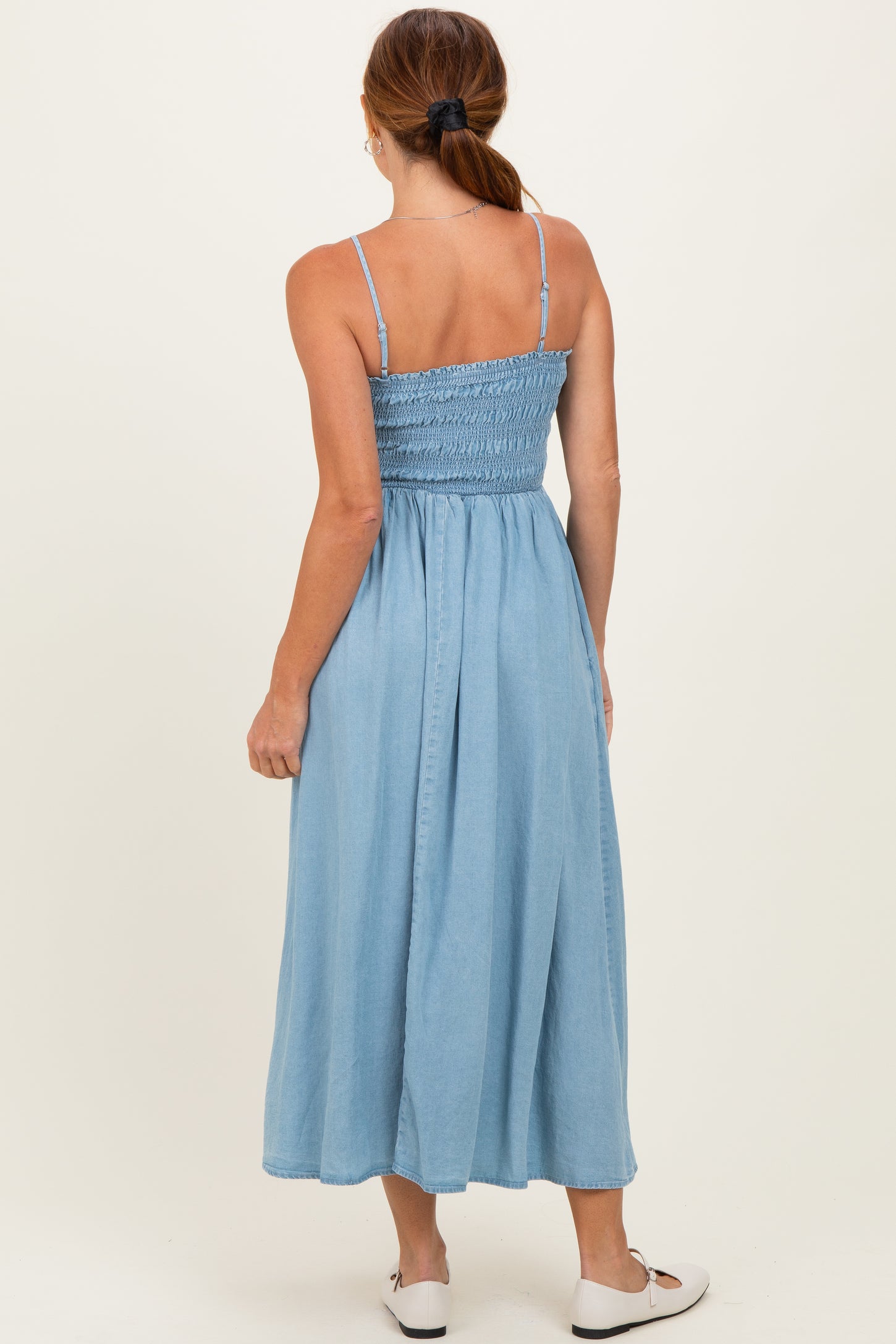 woman wearing a light blue maxi dress with smocked bodice and spaghetti straps, shown from the back