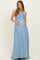 woman wearing a light blue maxi maternity dress with a halter neckline and holding her baby bump
